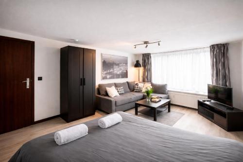 a bedroom with a large bed and a couch at Le Studio by La Reine City Center in Spa