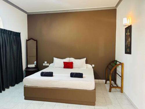 a bedroom with a bed with two red pillows on it at Hotel Marilyn in Negombo