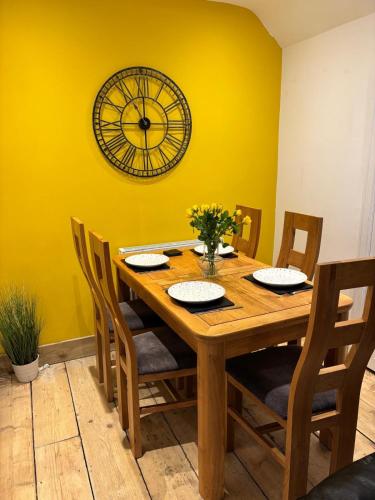 a dining room table with chairs and a clock on the wall at Evas place in Llandudno