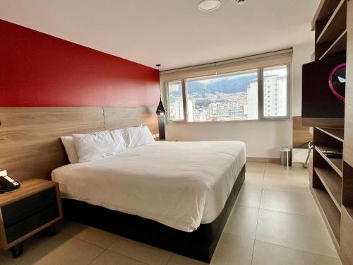 ein Schlafzimmer mit einem großen Bett und einer roten Wand in der Unterkunft The Place Hotel in Quito