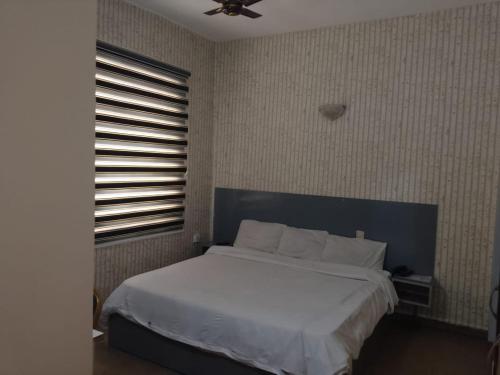 a bedroom with a white bed and a window at Transit Care Hotel in Port Harcourt