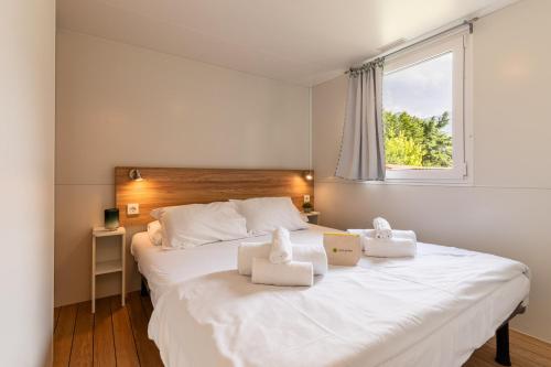 a bedroom with a large white bed with towels on it at Club del Sole Due Laghi Levico Family Collection in Levico Terme