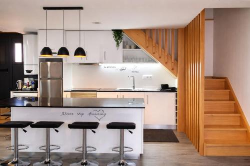 a kitchen with a counter with bar stools and a staircase at Refugio dos Coviais in Guarda