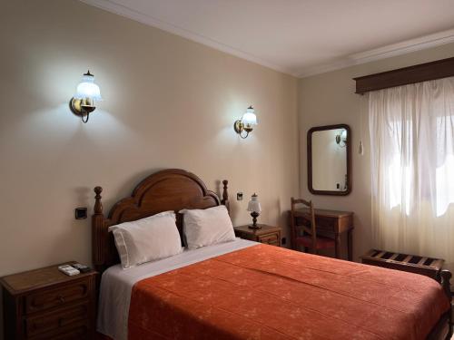 a bedroom with a large bed and a mirror at Residencial Deu-La-Deu by Hotel Dom Afonso in Monção