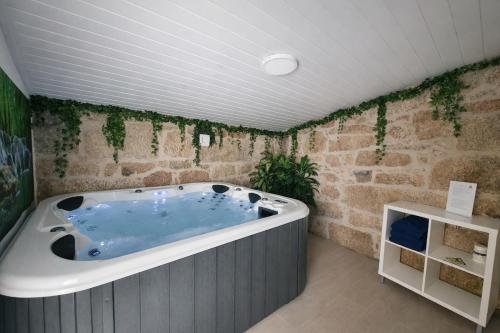 a bath tub in a room with a stone wall at Refugio dos Coviais in Guarda