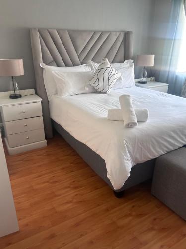 a bedroom with a large bed with white sheets and pillows at Modern , Spotless Townhouse in Quiet Estate - Pietermaritzburg in Pietermaritzburg