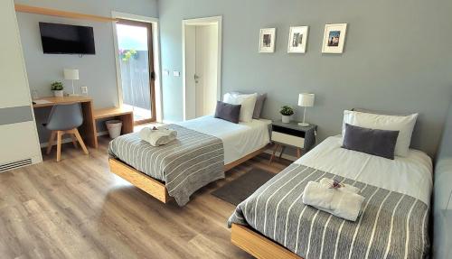 a bedroom with two beds and a desk with a computer at Jardim das Oliveiras - Suítes com Vista in Ponte de Lima
