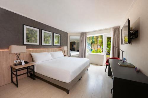 a bedroom with a large white bed and a desk at Torarica Resort in Paramaribo