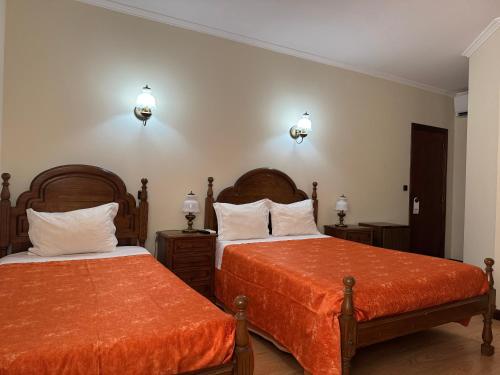 a bedroom with two beds with orange sheets at Residencial Deu-La-Deu by Hotel Dom Afonso in Monção