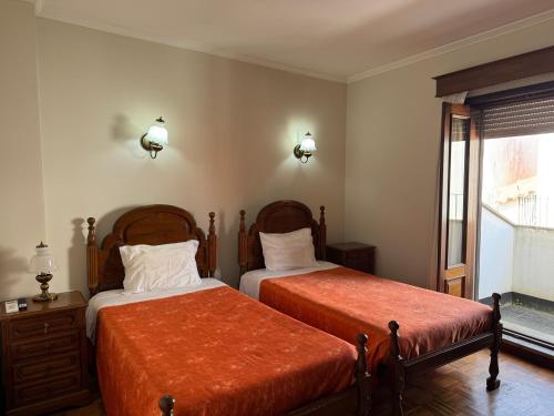 a bedroom with two beds and a window at Residencial Deu-La-Deu by Hotel Dom Afonso in Monção