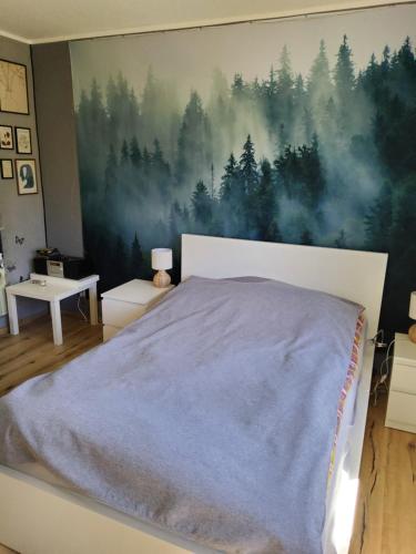 a bedroom with a large painting of trees on the wall at Eifelsteigzimmer Bruderherz in Gerolstein