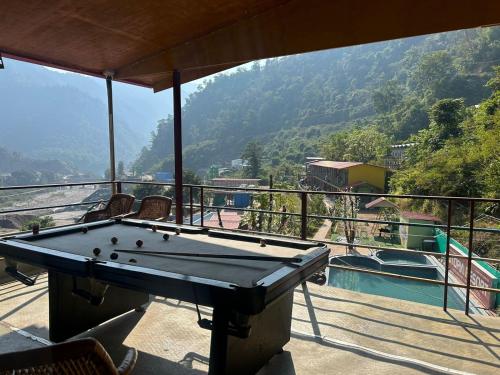 a pool table on a balcony with a view at Kaafirana Camps in Dhanaulti