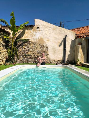 a man sitting in a swimming pool next to a house at AMEIO - Country House in Rio Maior