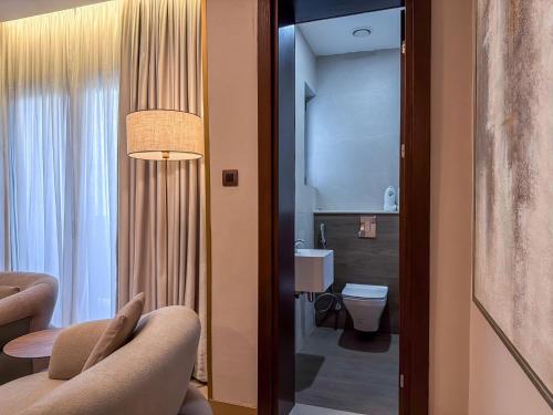 a room with a bathroom with a toilet and a mirror at The Lusso Hotel in Abuja