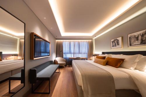 a hotel room with a large bed and a television at Laghetto Stilo Aeroporto in Porto Alegre