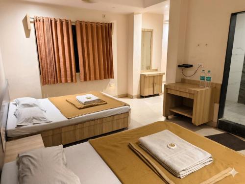 a hotel room with two beds and a bathroom at SD Blueberry Hotel in Shirdi