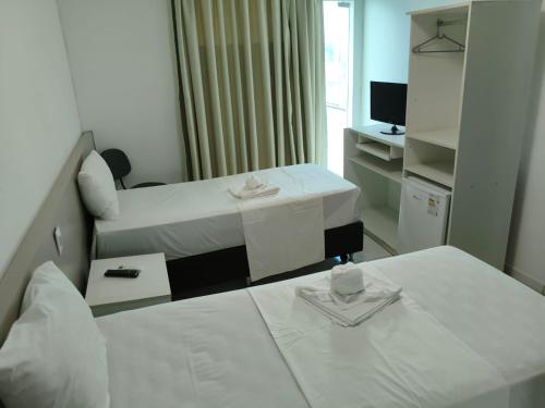 a hotel room with two beds and a television at Augustos Hotel in Santo Antônio de Jesus