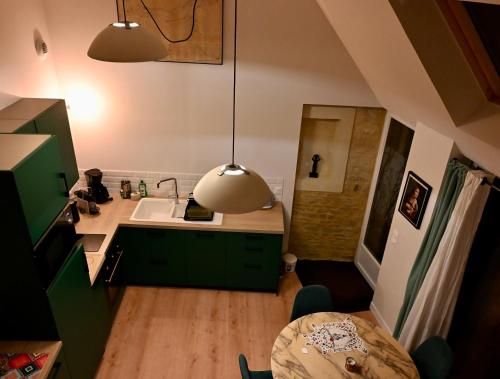 a kitchen with green cabinets and a sink and a table at Gîte Marangate Numéro 1 in Bazenville