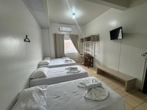 a room with three beds and a television in it at Hotel Indiana in Paragominas