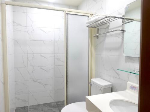 a bathroom with a shower and a toilet and a sink at Travel Island B&B in Beigan