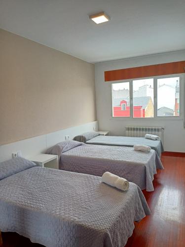 a room with three beds and two windows at dpCristal Sarria Centro in Sarria