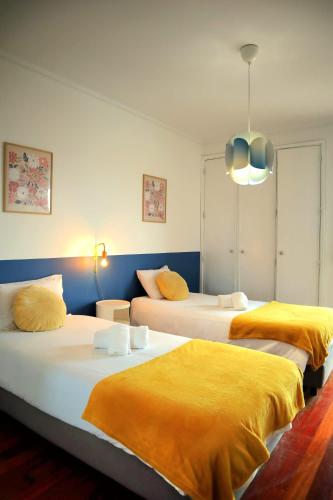 two beds with yellow sheets in a room at Yellow House Aveiro Smart TV and garage in Aveiro