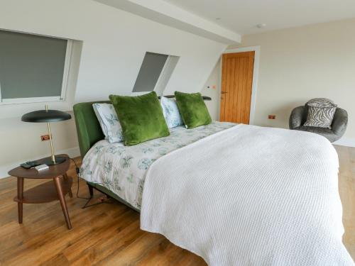 a bedroom with a large white bed with green pillows at Pengarnedd in Amlwch