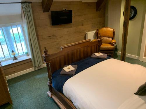 a bedroom with a bed and a chair and a television at The Kings Arms Pub in Stratton on the Fosse