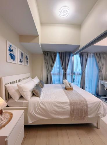 a bedroom with a large white bed and windows at Parksuites Tower 2 in Manila