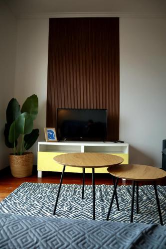 a living room with two tables and a tv at Yellow House Aveiro Smart TV and garage in Aveiro