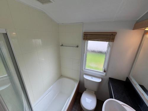 a bathroom with a tub and a toilet and a sink at Bag End, Near Porth Beach, Garden & Stream in Newquay Bay Resort