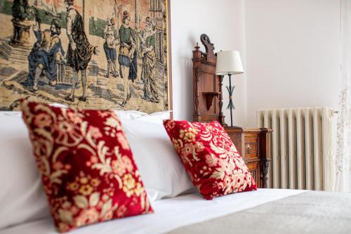a bed with two red pillows on top of it at Villa dei Domenicani in Copertino