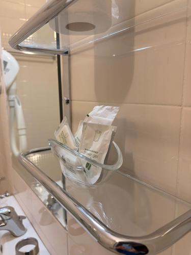 a glass shelf in a bathroom with some toiletries at City Hall in Catania