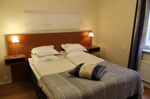 a bedroom with a bed with a headboard and two lamps at Teaterhotellet in Malmö