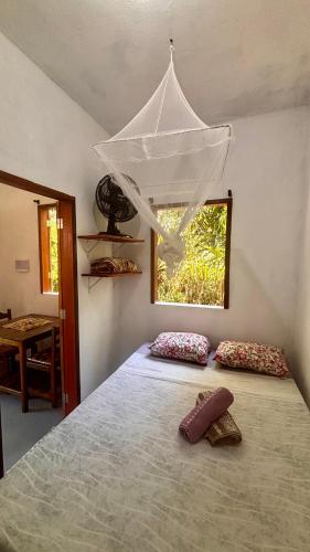 a bedroom with a bed with two pillows and a window at Taboca Chalé na Rua do Serrão in Cairu