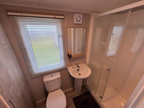 a bathroom with a toilet and a shower and a sink at Sun & Sand, Near Padstow, Seven Bays, Sleeps 6 in Saint Merryn