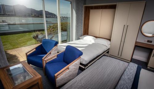 a bedroom with a bed and two blue chairs at The Quay Hotel and Spa in Conwy