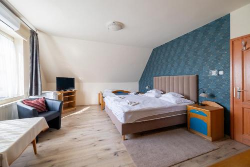 a bedroom with a bed and a chair in a room at Főnix Fogadó in Lenti