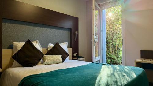 a bedroom with a large bed with a large window at The Originals City, Hôtel La Siesta, Annonay Est in Davézieux