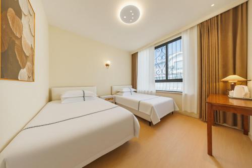 a hotel room with two beds and a window at Boyi Apartment - Shanghai National Convention and Exhibition Center Branch in Shanghai