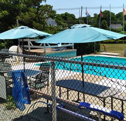 two blue umbrellas and chairs next to a swimming pool at Pineapple Inn in North Attleboro
