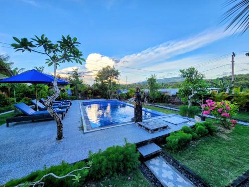a backyard with a swimming pool and an umbrella at RR Cottage in Nusa Penida