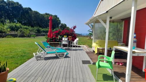 a deck with chairs and a table with a table at Cabana Papoila in Colares