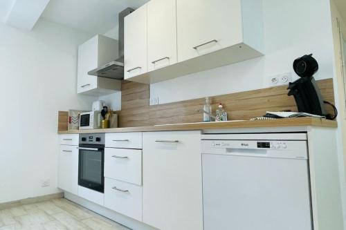 a white kitchen with white cabinets and appliances at Cognac Gare Classé 3 in Cognac