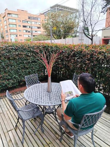 a man sitting at a table with a laptop at Prisma Suites Chico 94 in Bogotá