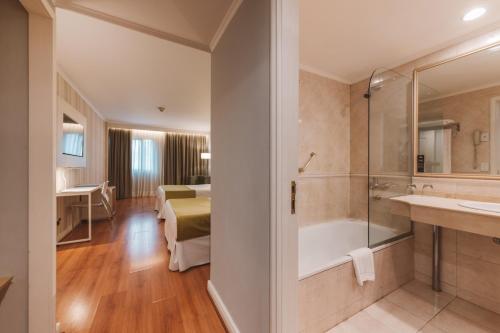 a bathroom with a tub and a bedroom with a bed at Pestana Buenos Aires in Buenos Aires