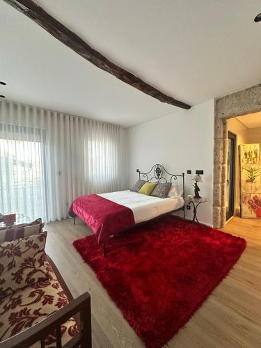 a bedroom with a large bed and a red rug at Azenha Ah Bô! in Alijó