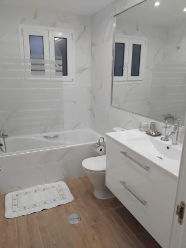 a white bathroom with a tub and a toilet and a sink at Mi Capricho in Sitio de Calahonda