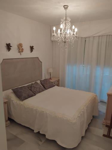 a bedroom with a white bed and a chandelier at Mi Capricho in Sitio de Calahonda