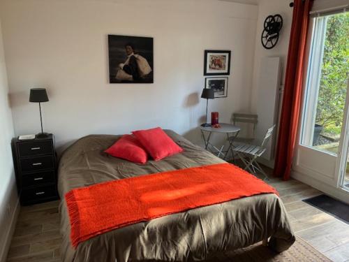 a bedroom with a bed with two red pillows at Les Mûres in Saint-Lunaire
